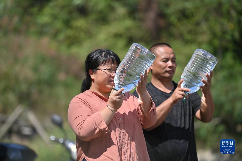楊寧（左）在查看村民剛剛采集的水樣，為山泉水引水工程做準備（10月8日攝）。新華社記者 黃孝邦 攝